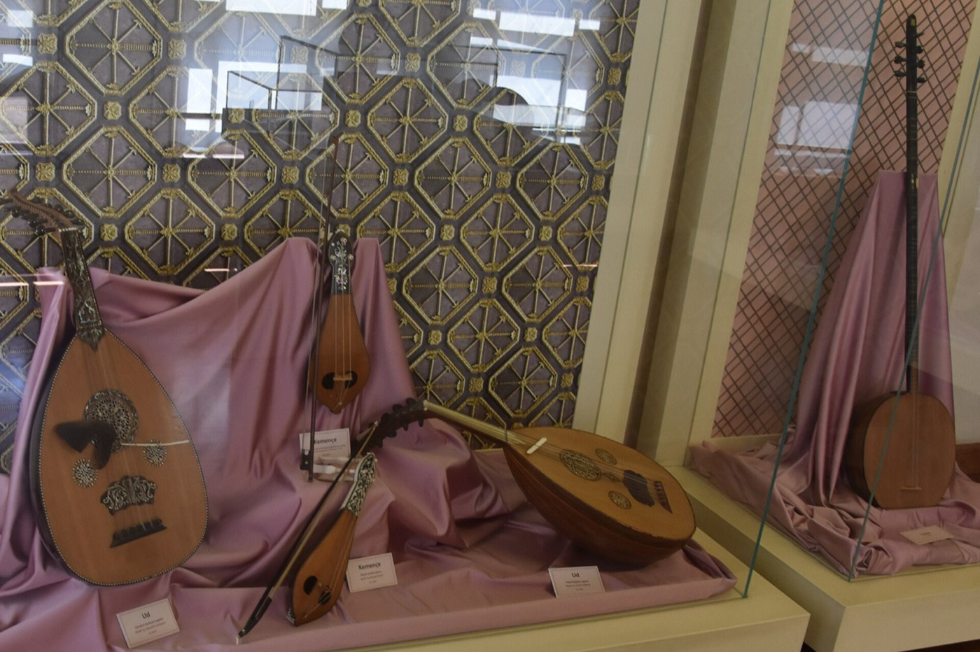 Ouds and other stringed instruments laid out on draped fabric in a glass case in the pavilion's music museum