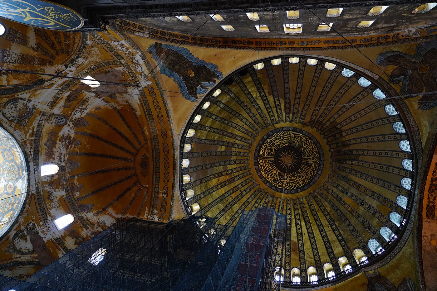 The main dome of Hagia Sophia from below, ringed by its band of windows, with restoration scaffolding rising into the space