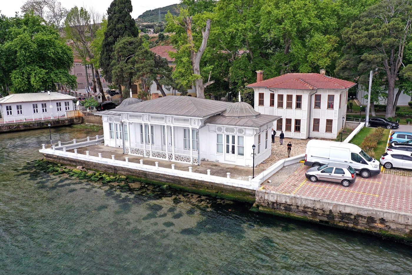 Aerial view of the white timber Kaiser Wilhelm Pavilion on its quay at Hereke, with the sea in front and trees and older buildings behind