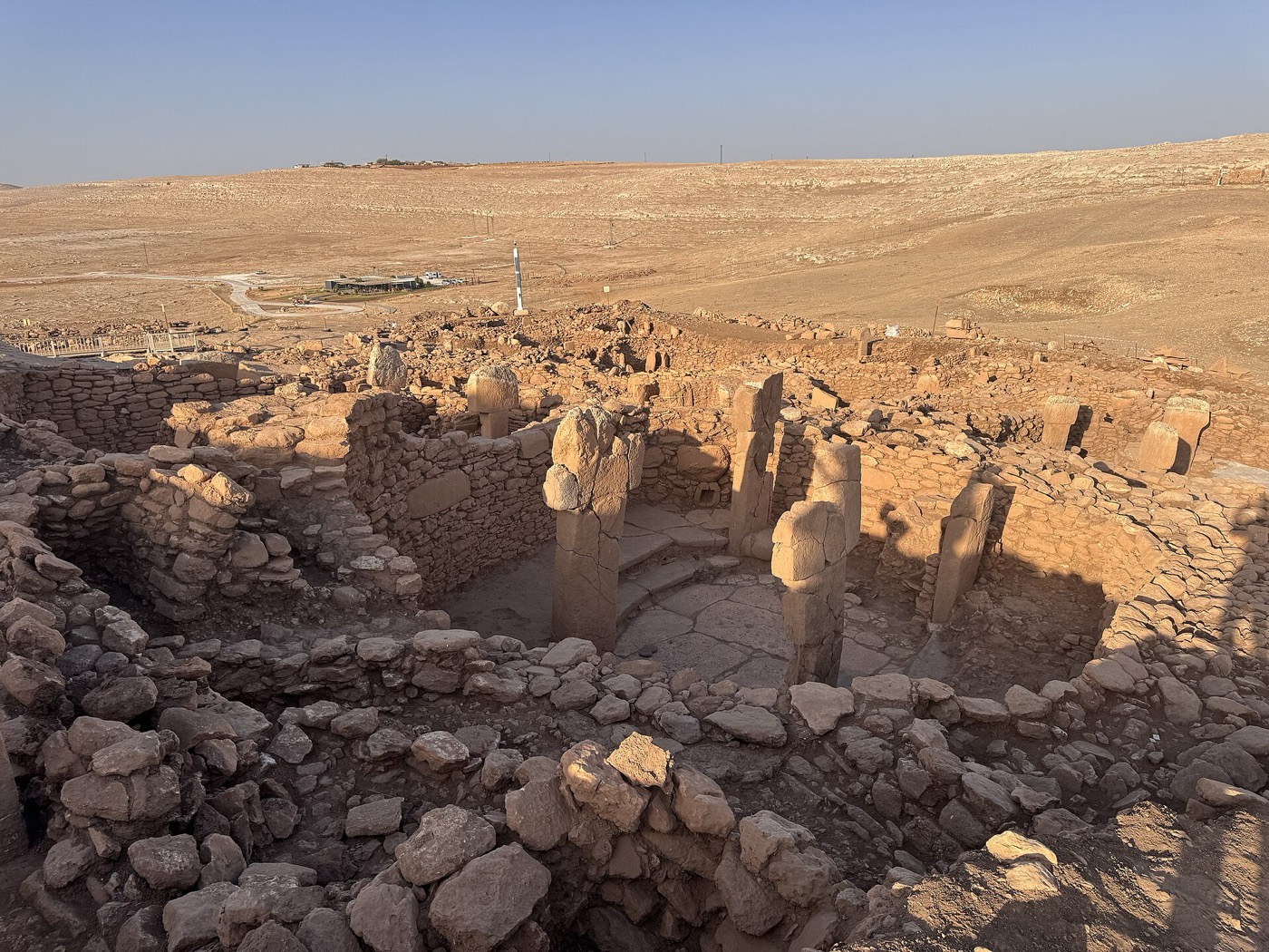 Rows of excavated stone pillars at Karahantepe, with the open steppe of the Tek Tek Mountains beyond