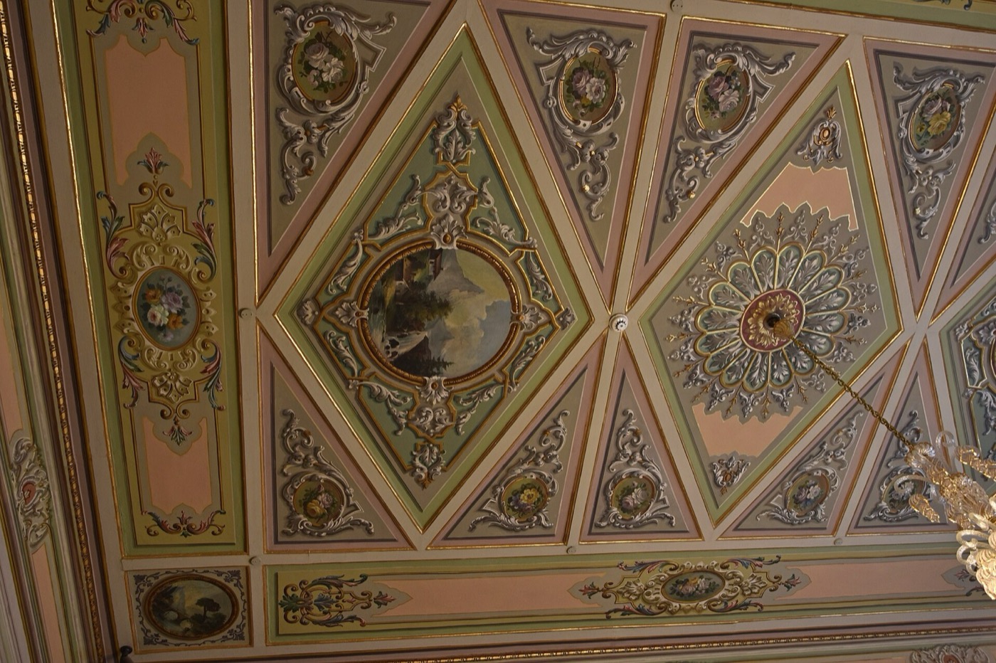 A ceiling in the Crown Prince's Apartment divided into gilded diamond and triangle panels, painted with a landscape medallion, flower garlands and a central rosette