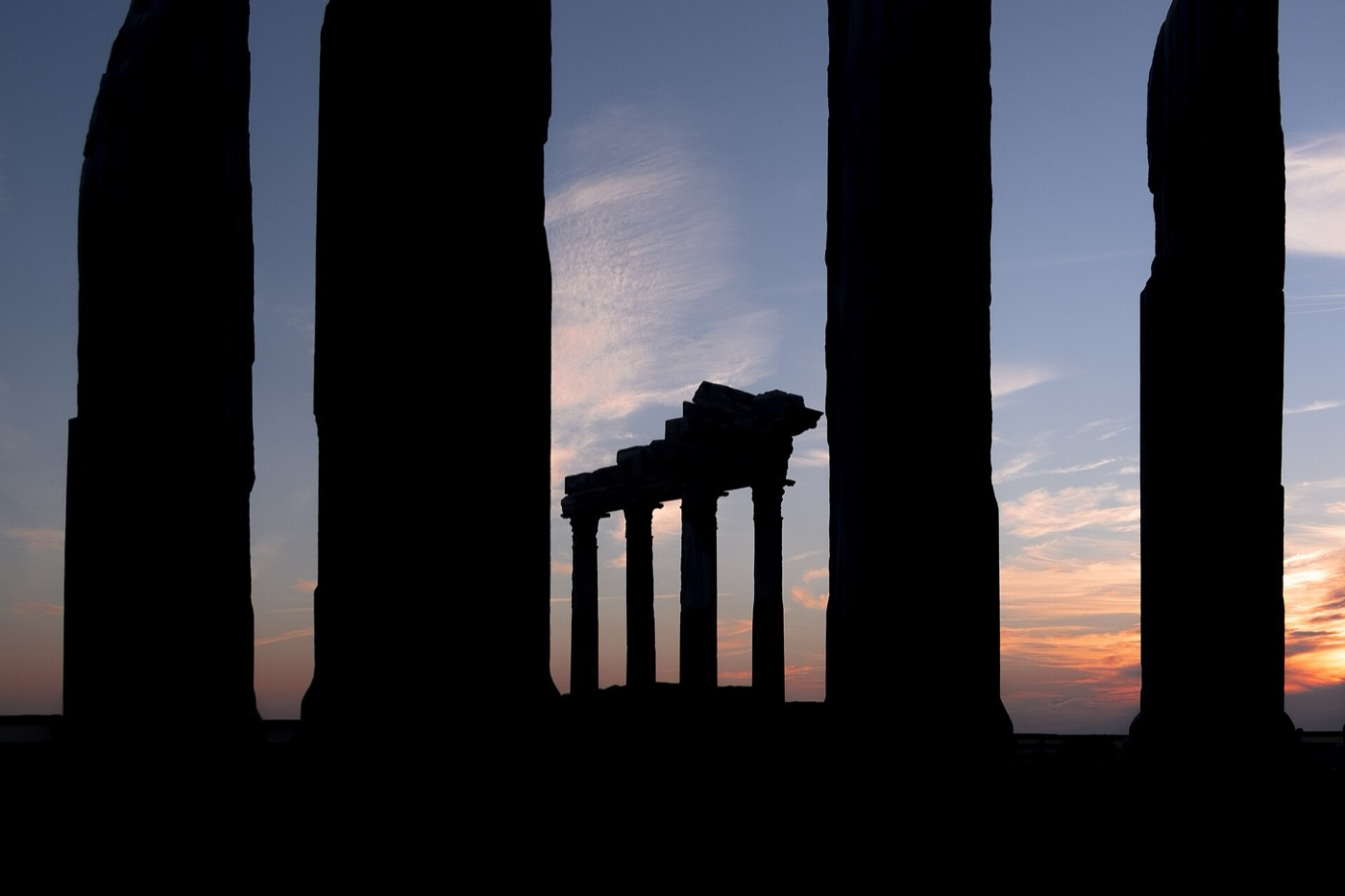 The columns of the Temple of Apollo silhouetted against the sunset over the sea