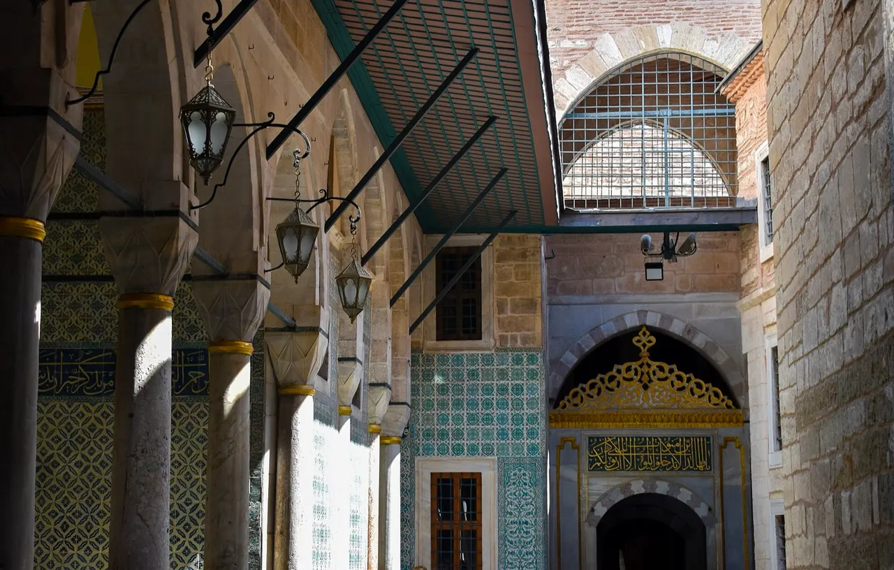 A narrow tiled colonnade in the Harem of Topkapı Palace, with hanging lanterns