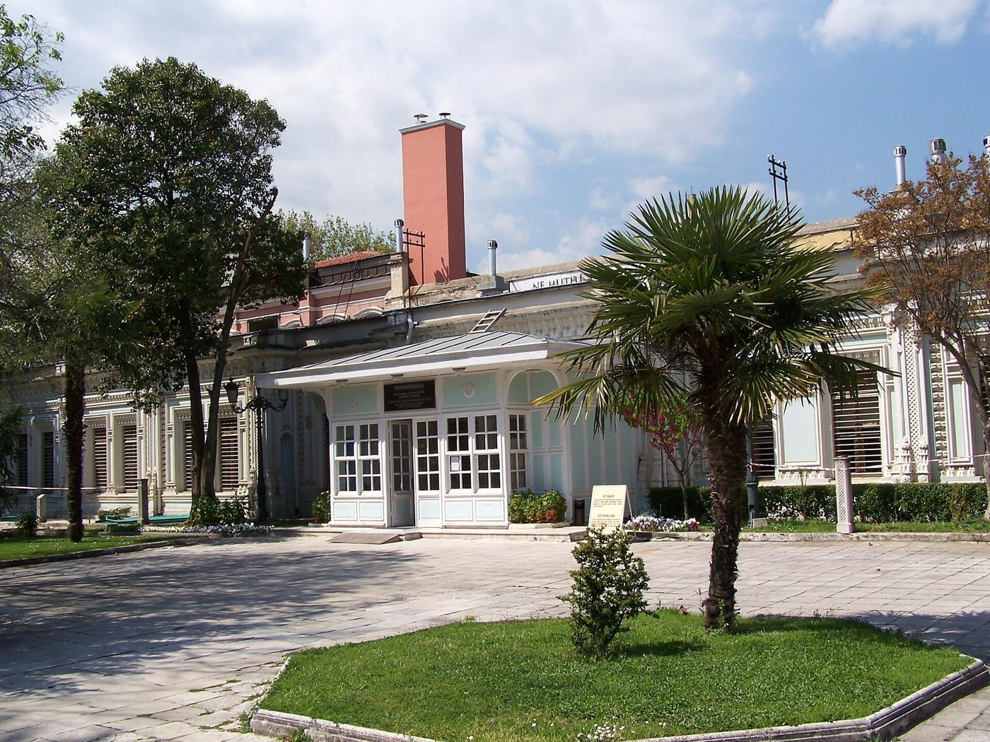 The low Çit Pavilion at Yıldız Palace behind a palm tree and a small lawn