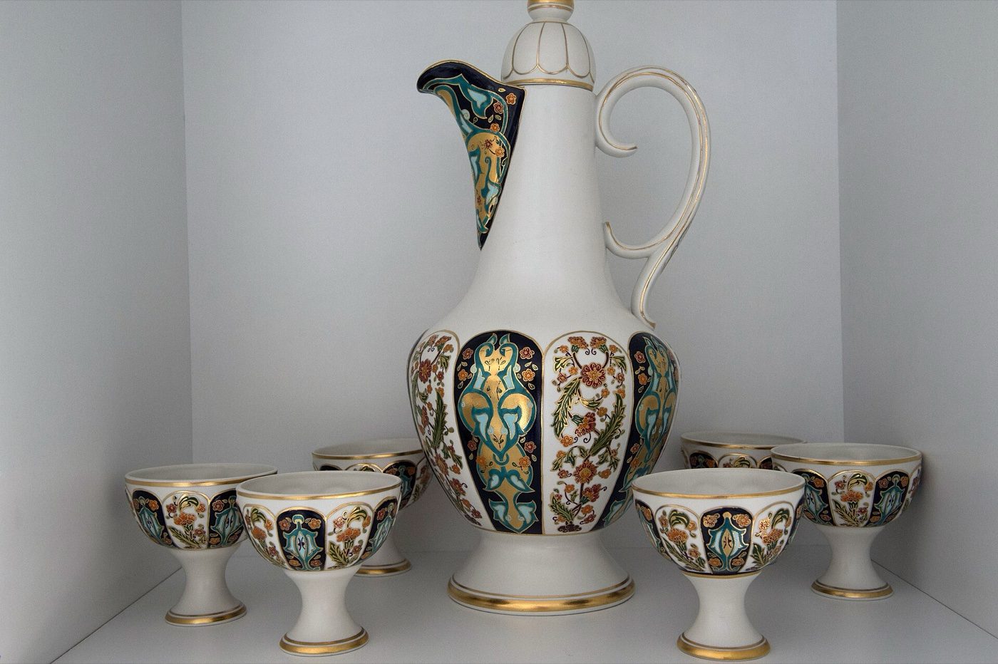 A porcelain ewer and cups with coloured floral panels and gilding, products of the Yıldız Porcelain Factory on a shop shelf